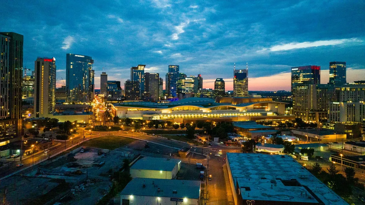 A sweeping view of the Nashville city skyline at dusk, with illuminated buildings under a vibrant sky. The city’s energy, nightlife, and urban vibrancy are on full display, highlighting the area’s appeal for both productivity and relaxation.