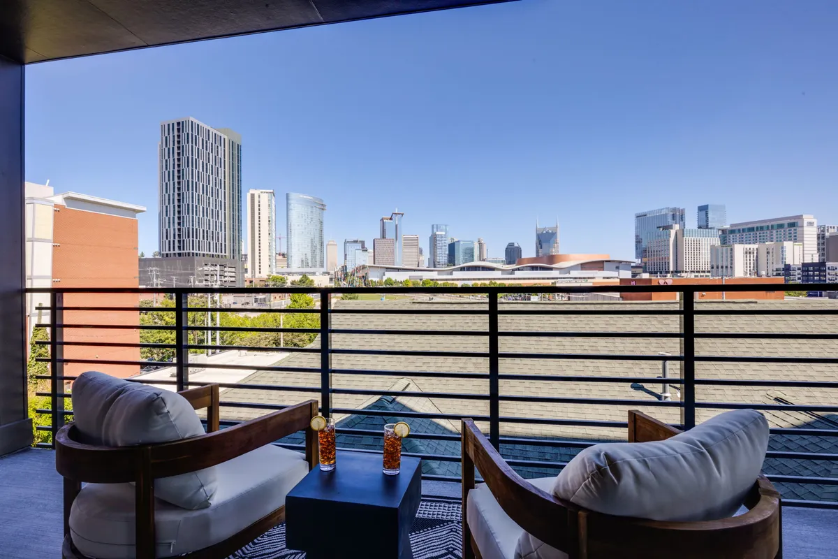 An outdoor rooftop seating area overlooking the city skyline, with drinks on the table and a relaxed, contemporary vibe. The space invites residents to enjoy panoramic views and socialize in a vibrant setting.